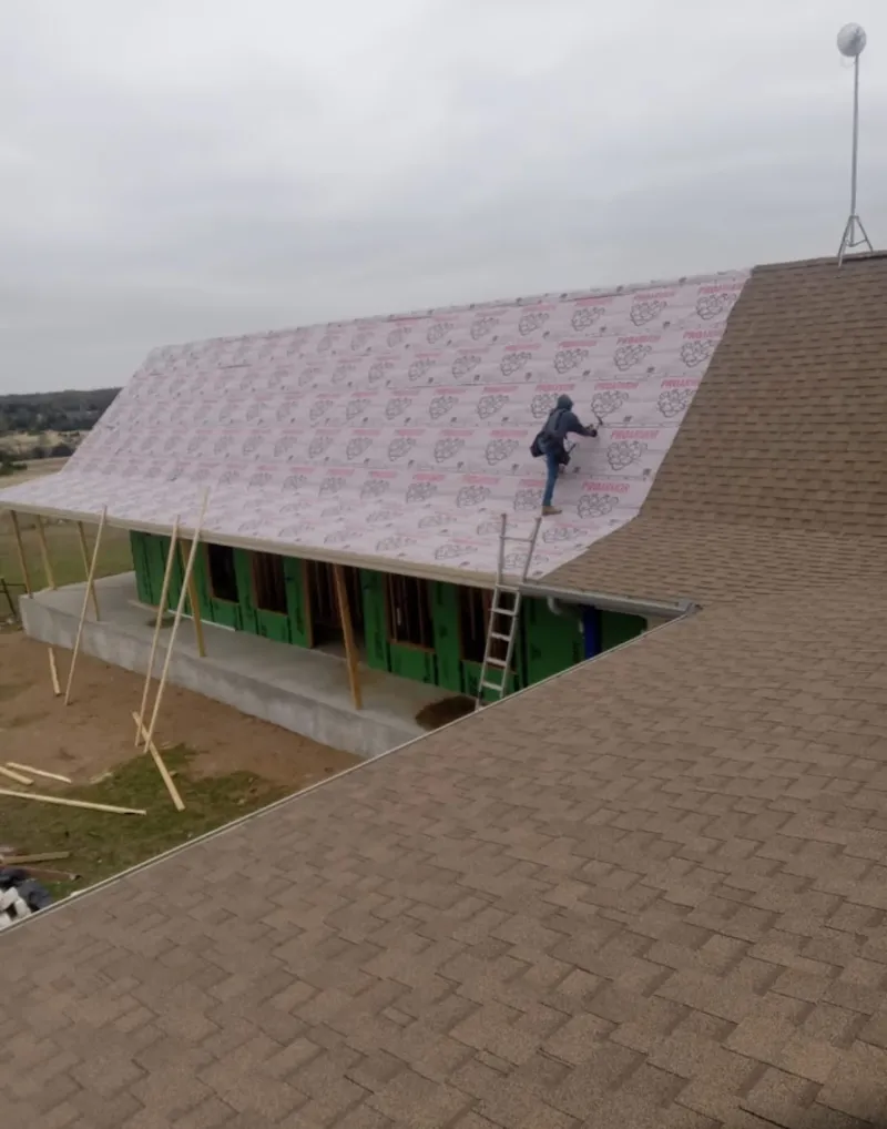 Worker preparing underlayment for a metal roof installation in East Longmeadow